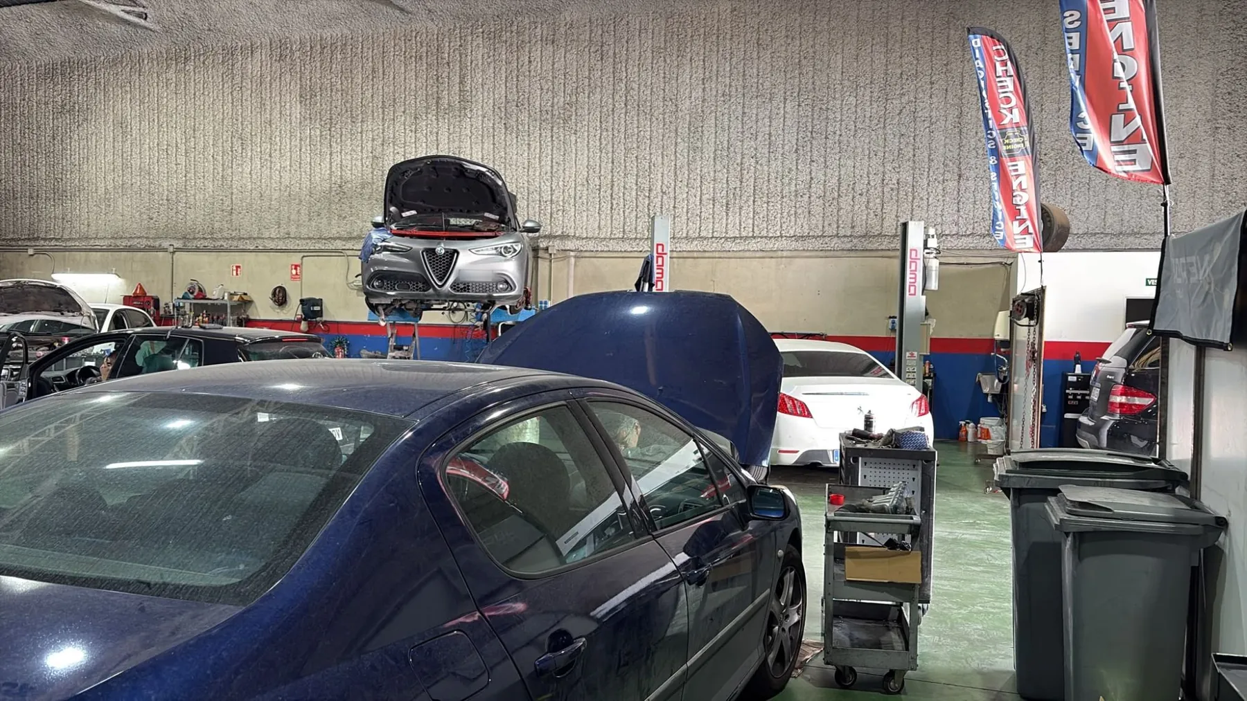 Interior de Talleres Integrales, con un coche en el elevador y varios vehículos en reparación